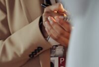 Journalist in a beige coat taking notes with a visible press badge.